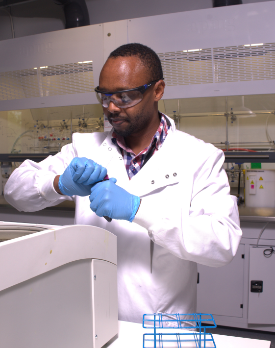 Man with blue gloves on at a lab opening a piece of science equipment